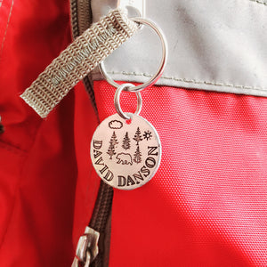 stamped kids' backpack id tag with forest scene with a bear on a red backpack