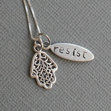 Load image into Gallery viewer, Silver &quot;resist&quot; oval pendant with filigree hamsa charm